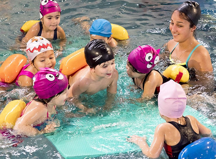 niños en la piscina con profesor de natación