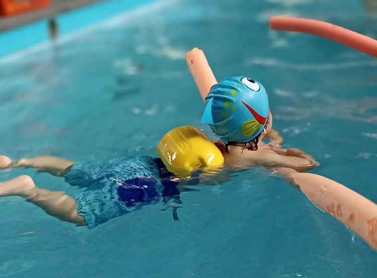 niños en la piscina con profesor de natación